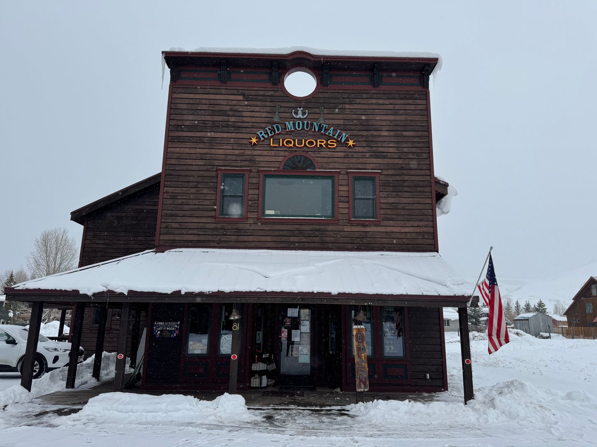 A large wooden building covered in snow with an american flag in front of it.