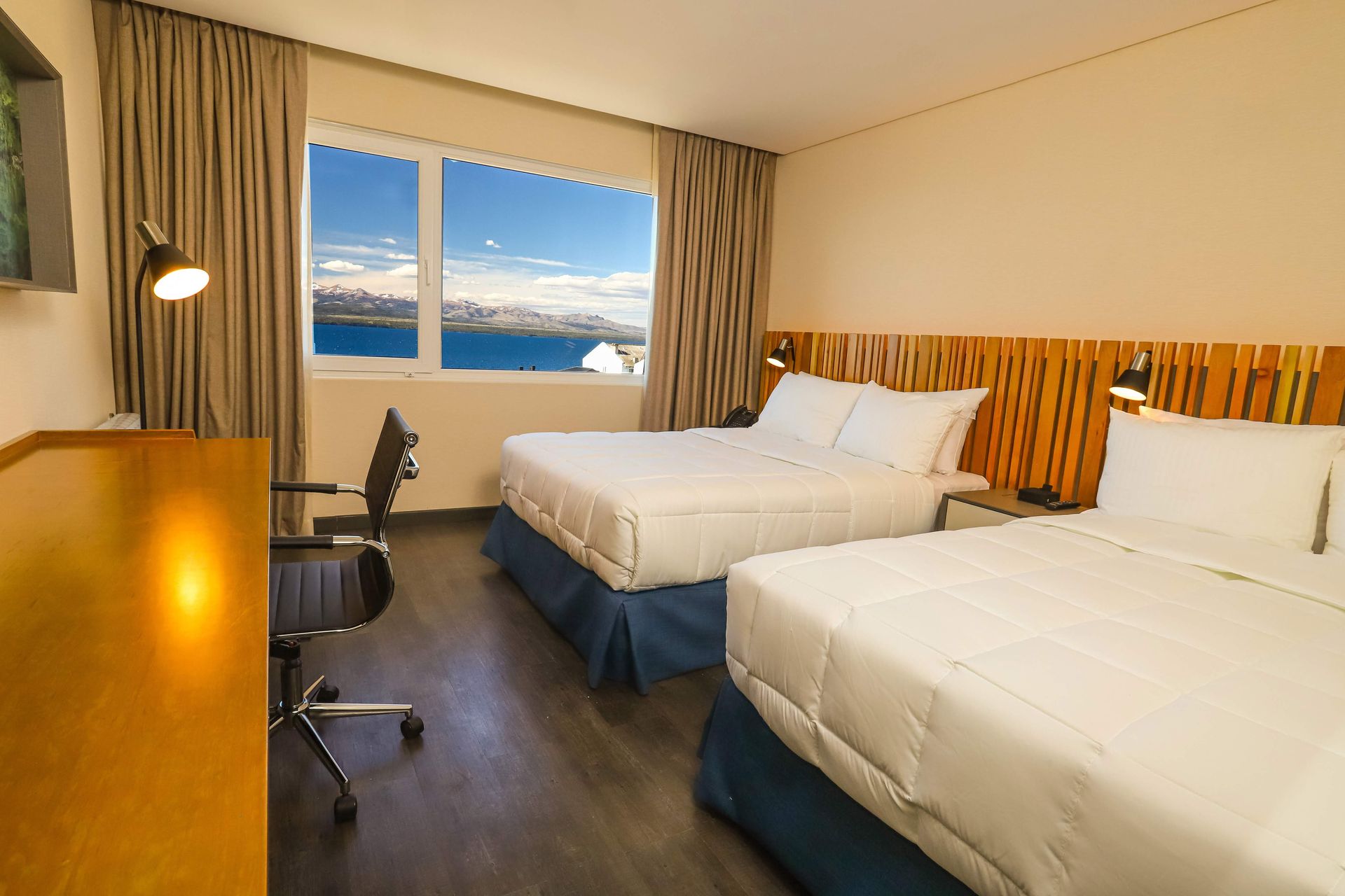 Una habitación de hotel con dos camas y un escritorio con vista al mar.