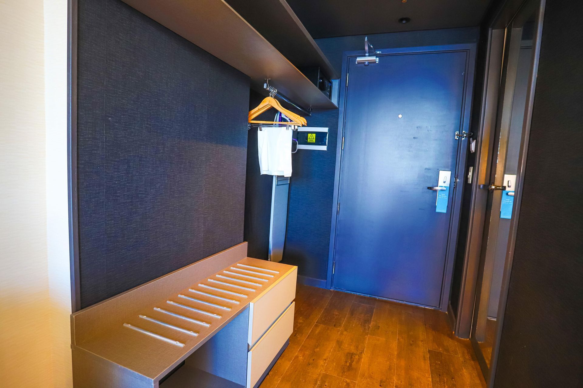Una habitación de hotel con una puerta azul y un banco.