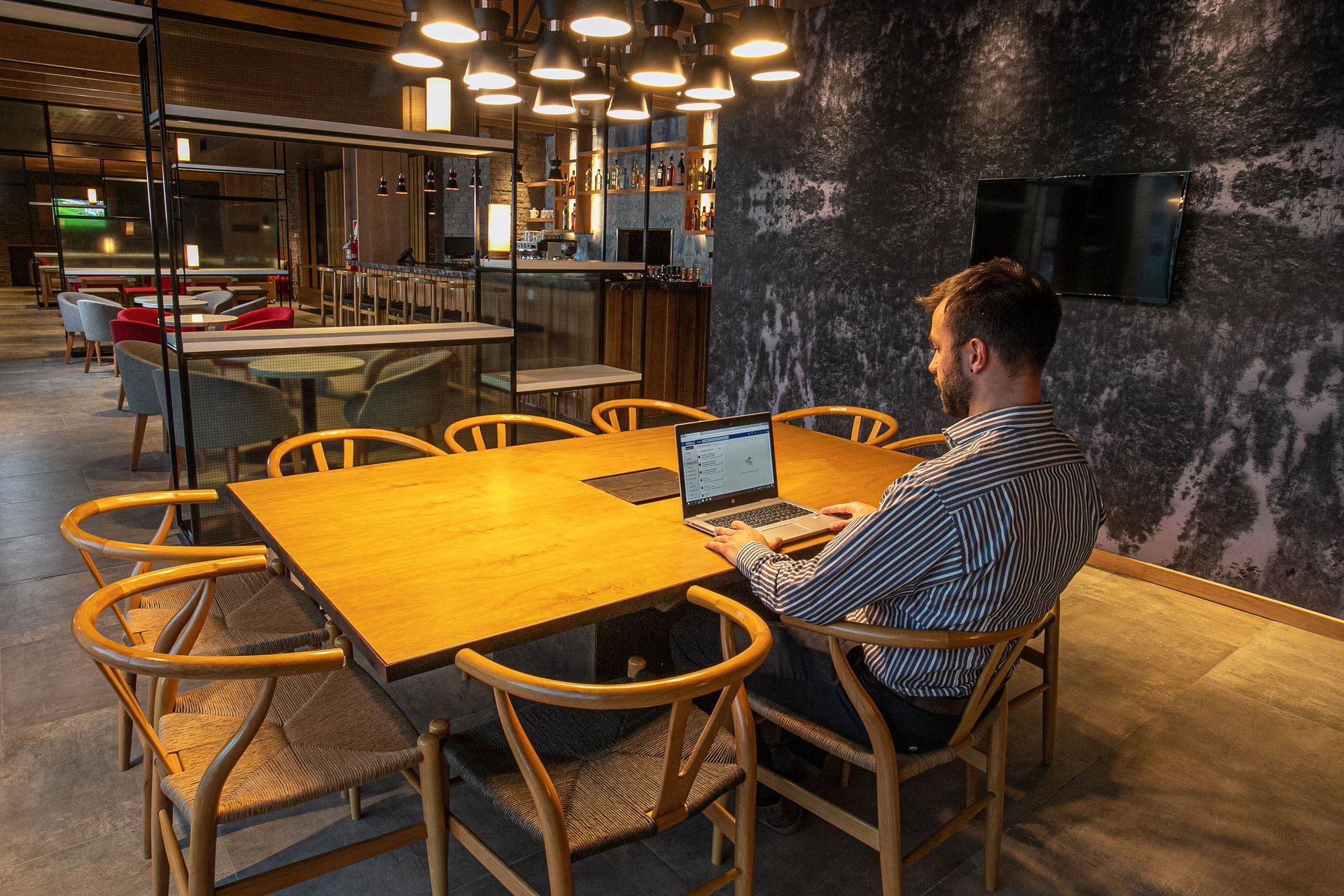 Un hombre está sentado en una mesa usando una computadora portátil.