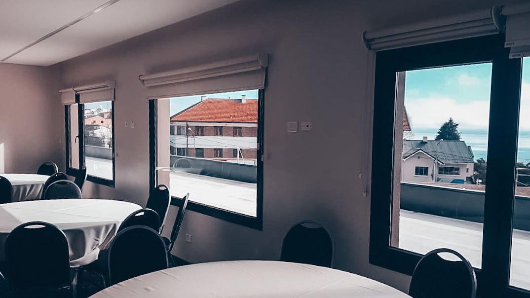 Una sala con mesas y sillas y una vista de un edificio a través de las ventanas.