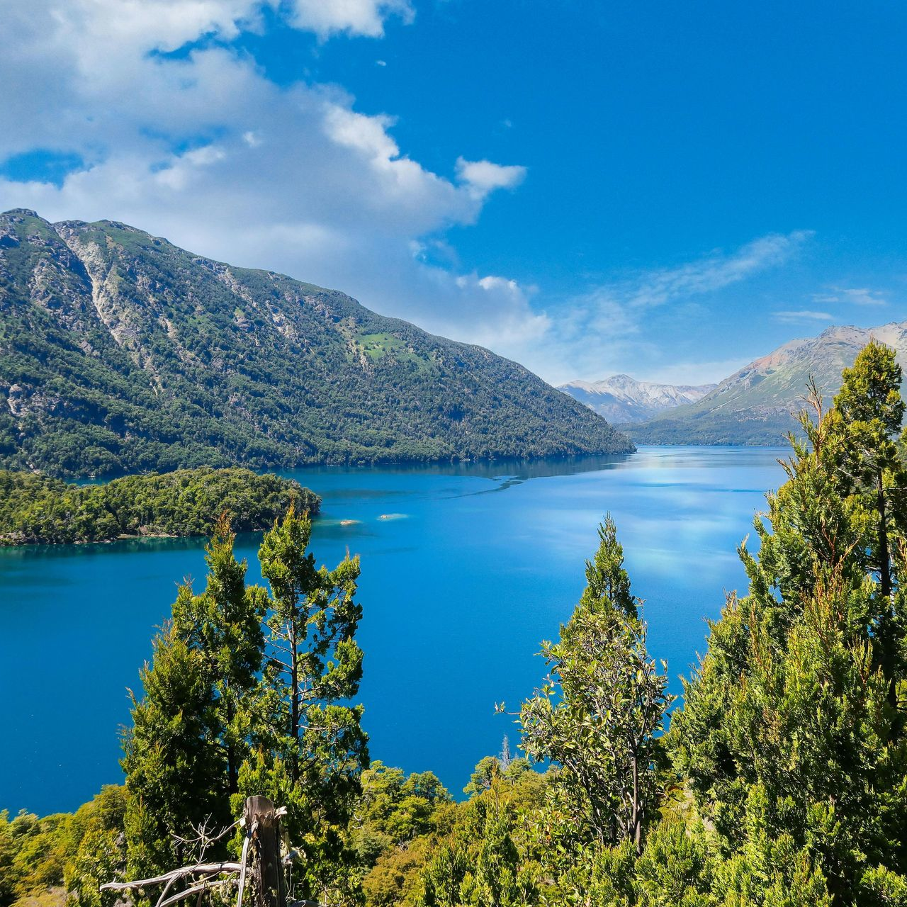 Un lago con montañas al fondo y rocas en primer plano.