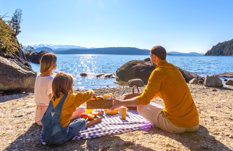 Un hombre y dos niños están haciendo un picnic en la playa.