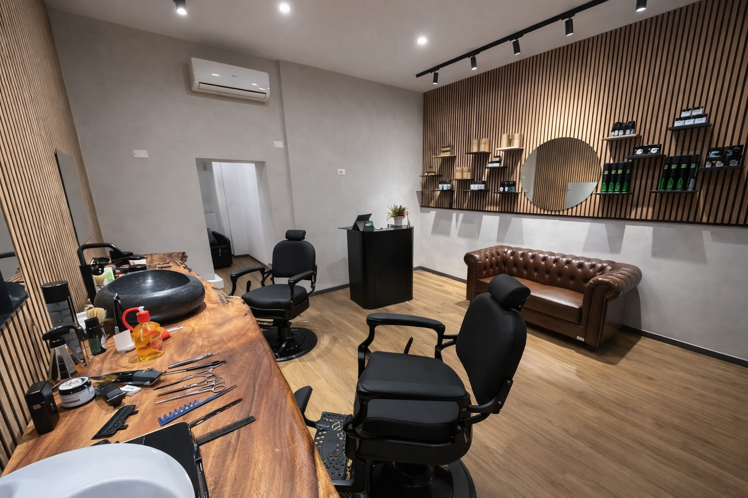 Postazione di lavoro del barbiere con tagliacapelli, forbici, spazzole, oli e uno specchio che riflette una sedia sfocata.