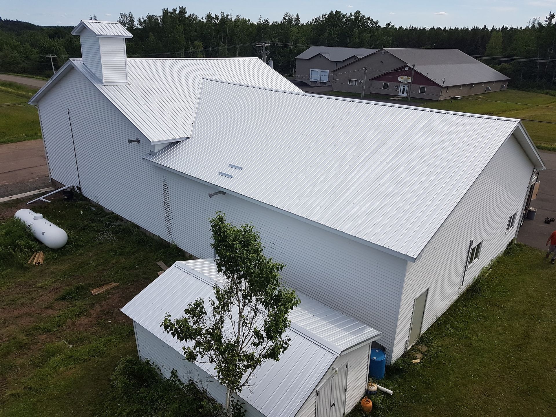 An aerial view of a white barn with a white roof.