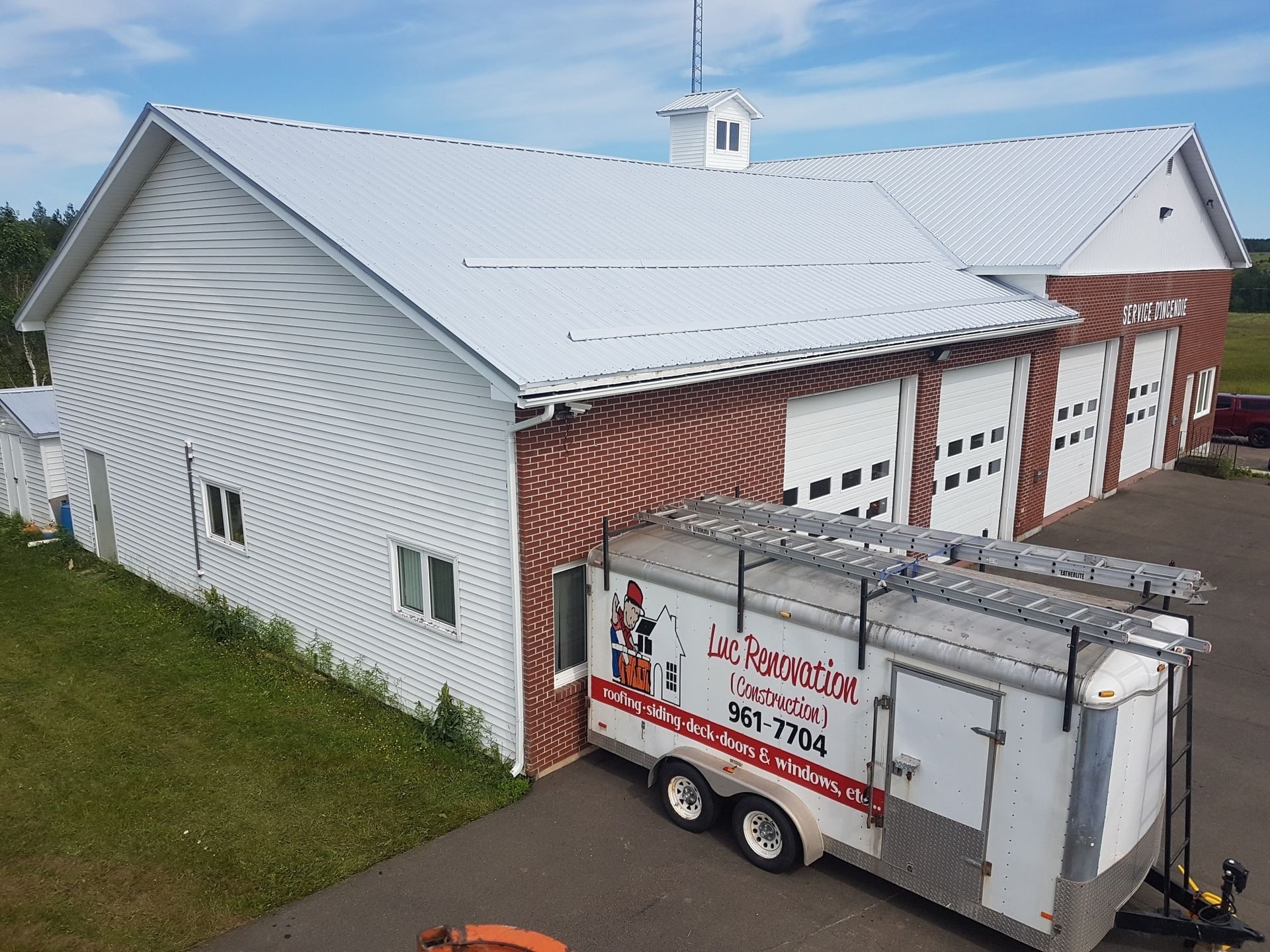 A trailer is parked in front of a large white building.