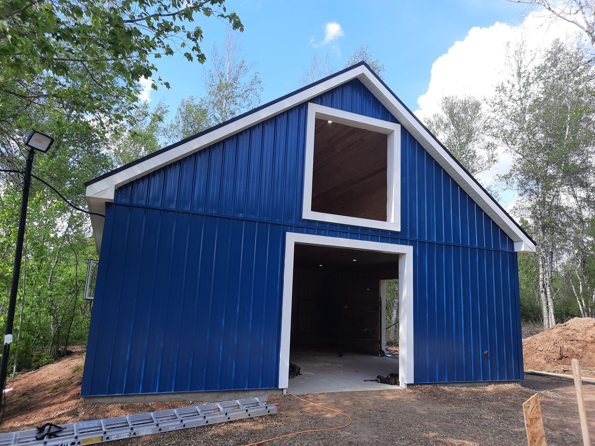 A blue barn with a white trim is sitting on top of a dirt hill.