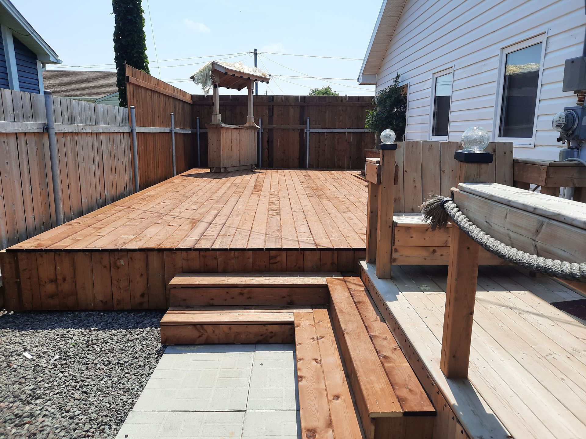 A wooden deck with stairs and a fence in the backyard of a house.