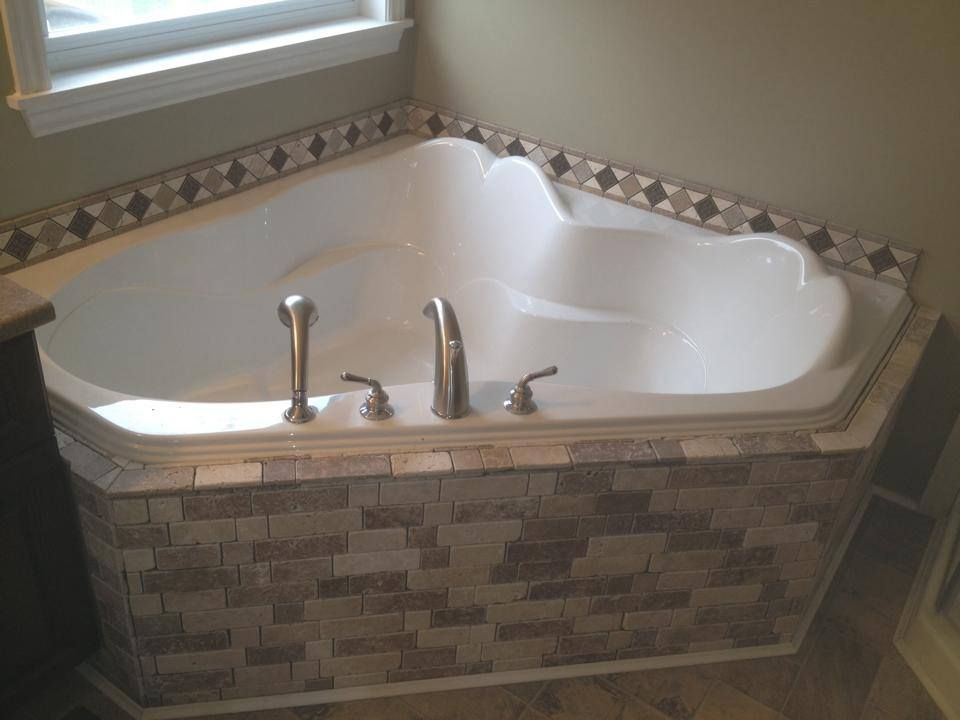 A jacuzzi tub is sitting in the corner of a bathroom next to a window.