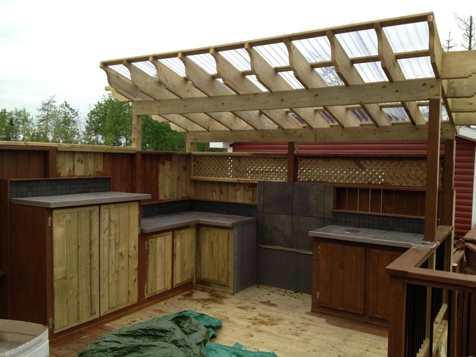A wooden pergola is being built over a wooden kitchen.