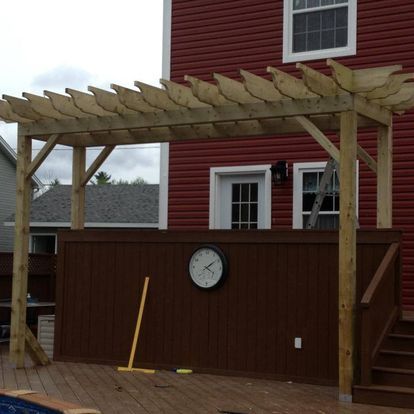 A red house with a wooden pergola and a clock on the wall