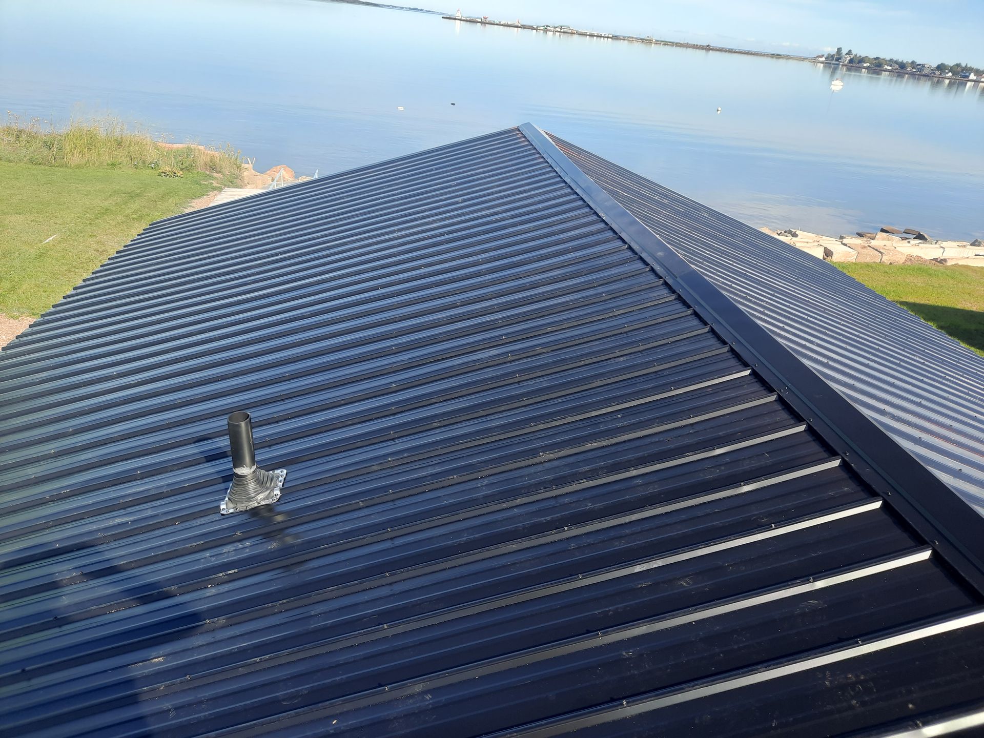 A black roof with a chimney on it overlooking a body of water