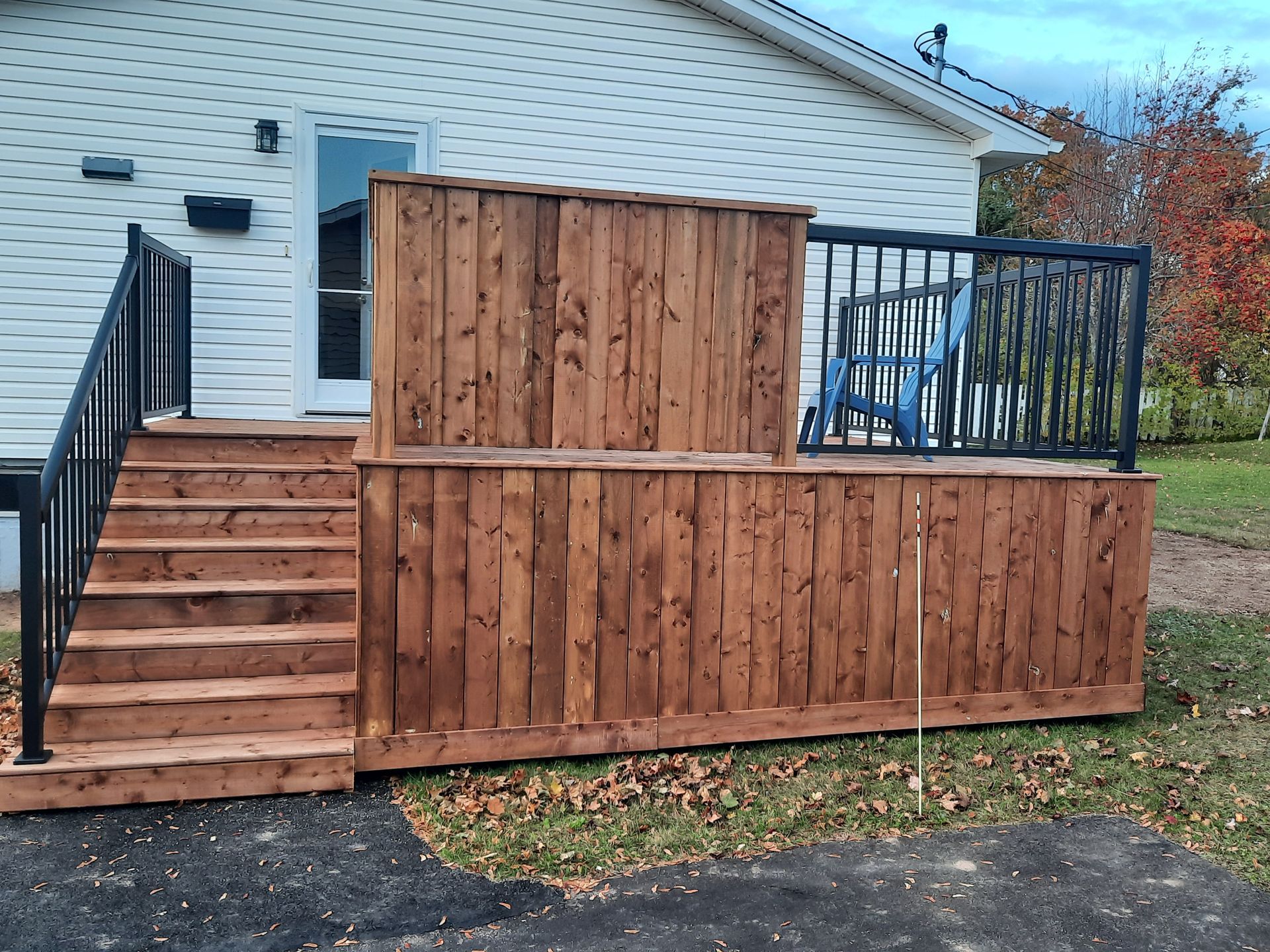 A wooden deck with stairs and a fence in front of a house.