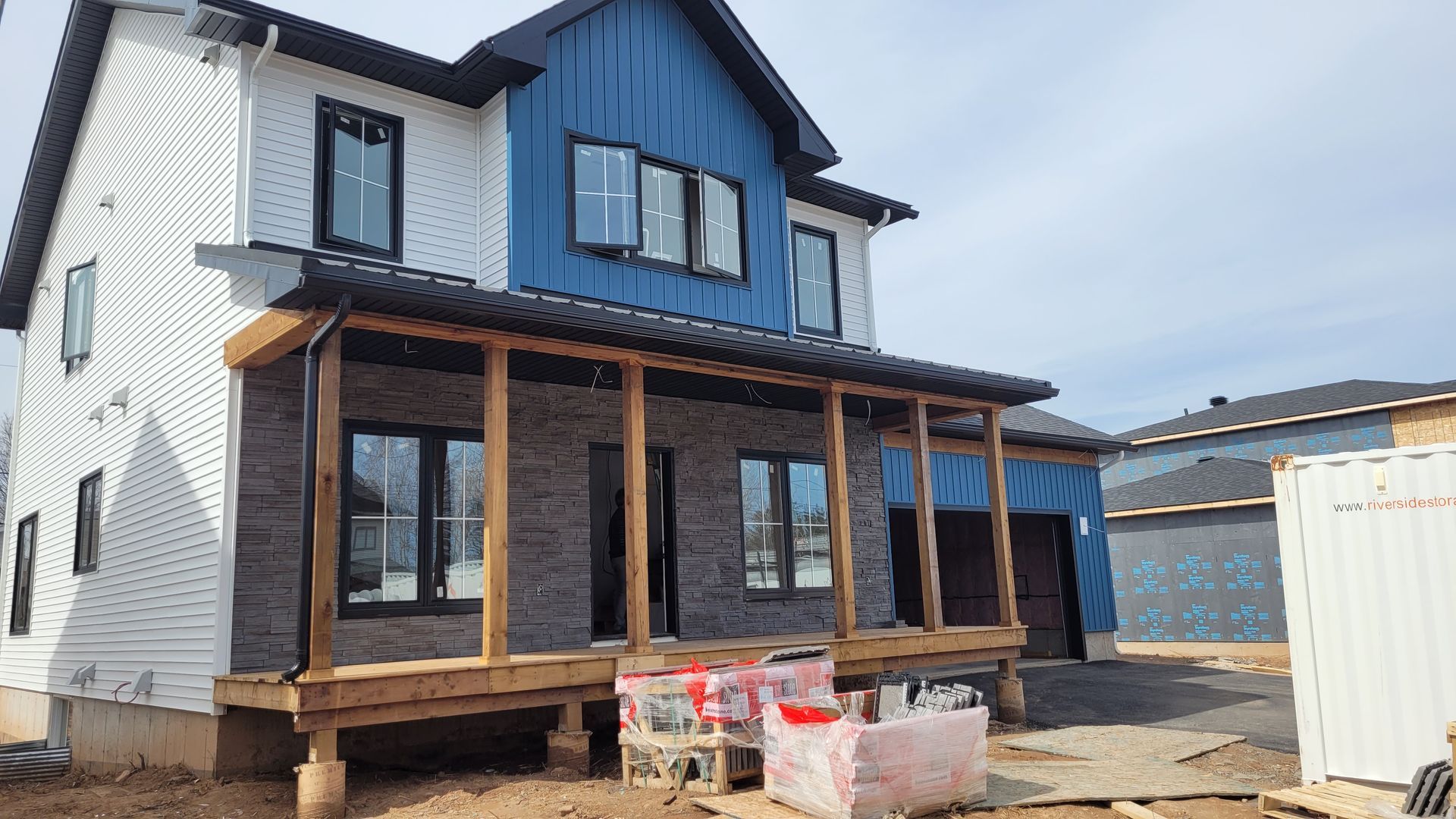 A house is being built with a blue and white siding and a porch.