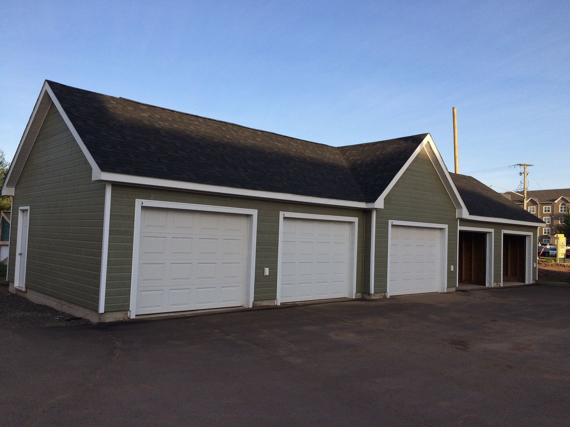 A row of garages with green siding and white doors