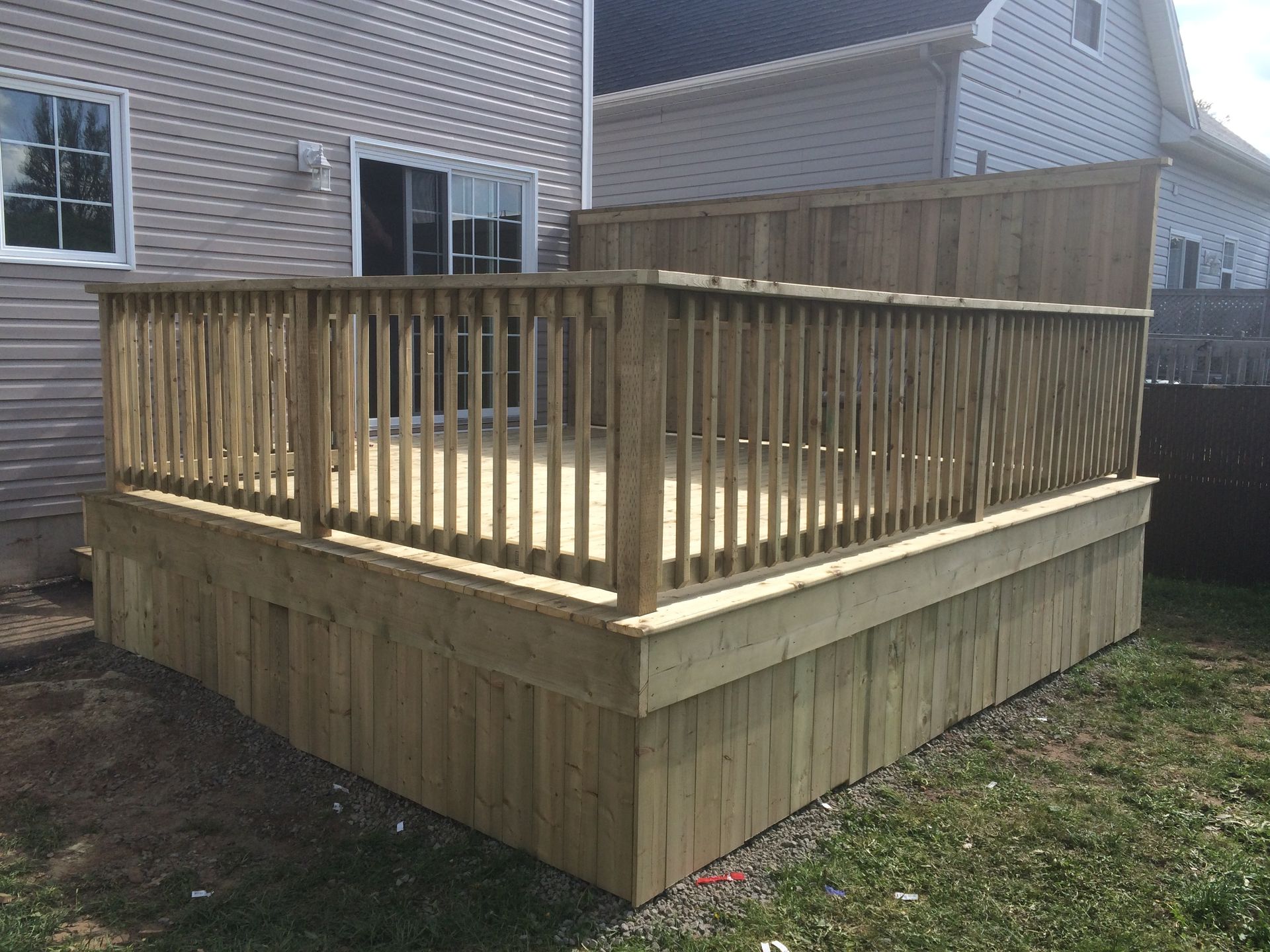 A wooden deck with a railing in front of a house.
