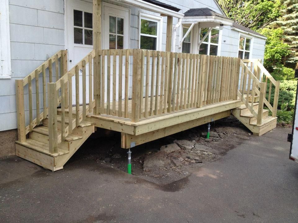 A wooden deck with stairs is in front of a house.