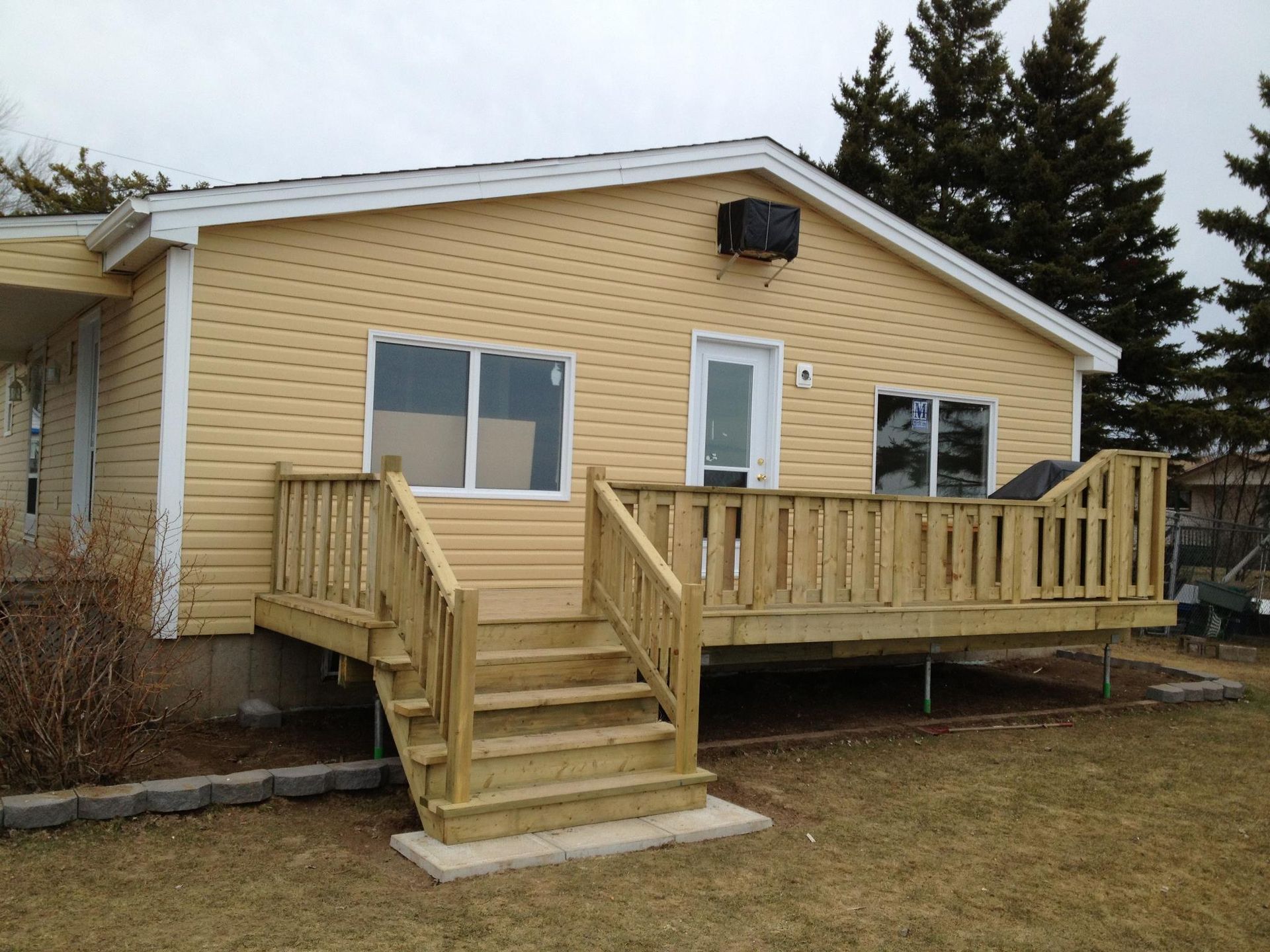 A yellow house with a wooden deck and stairs