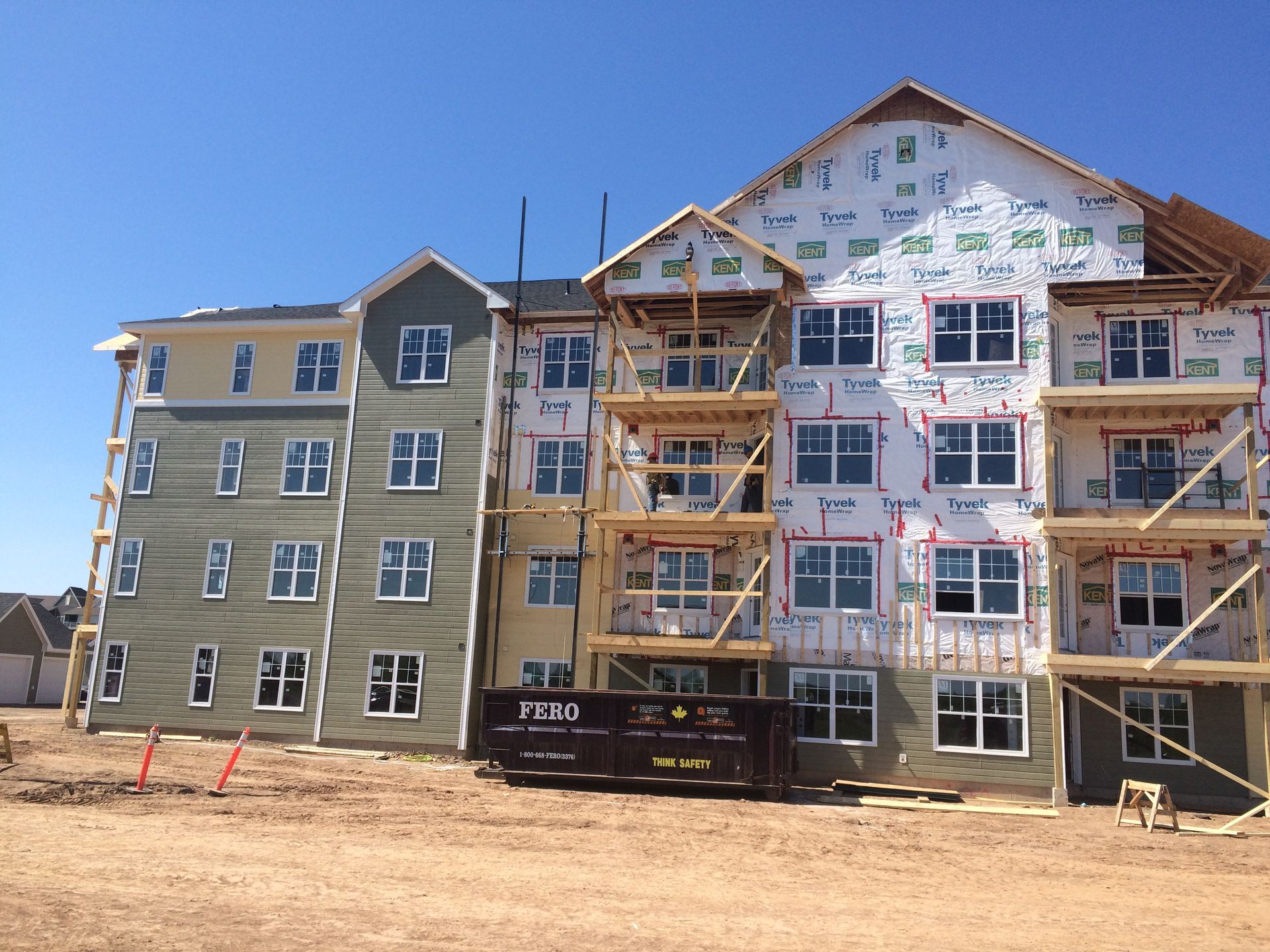 Multi-story apartment building under construction with scaffolding and exposed framing on a clear day
