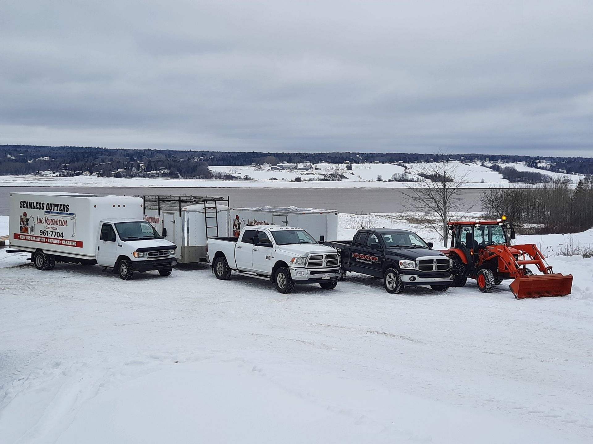 A group of trucks and tractors are parked in the snow.