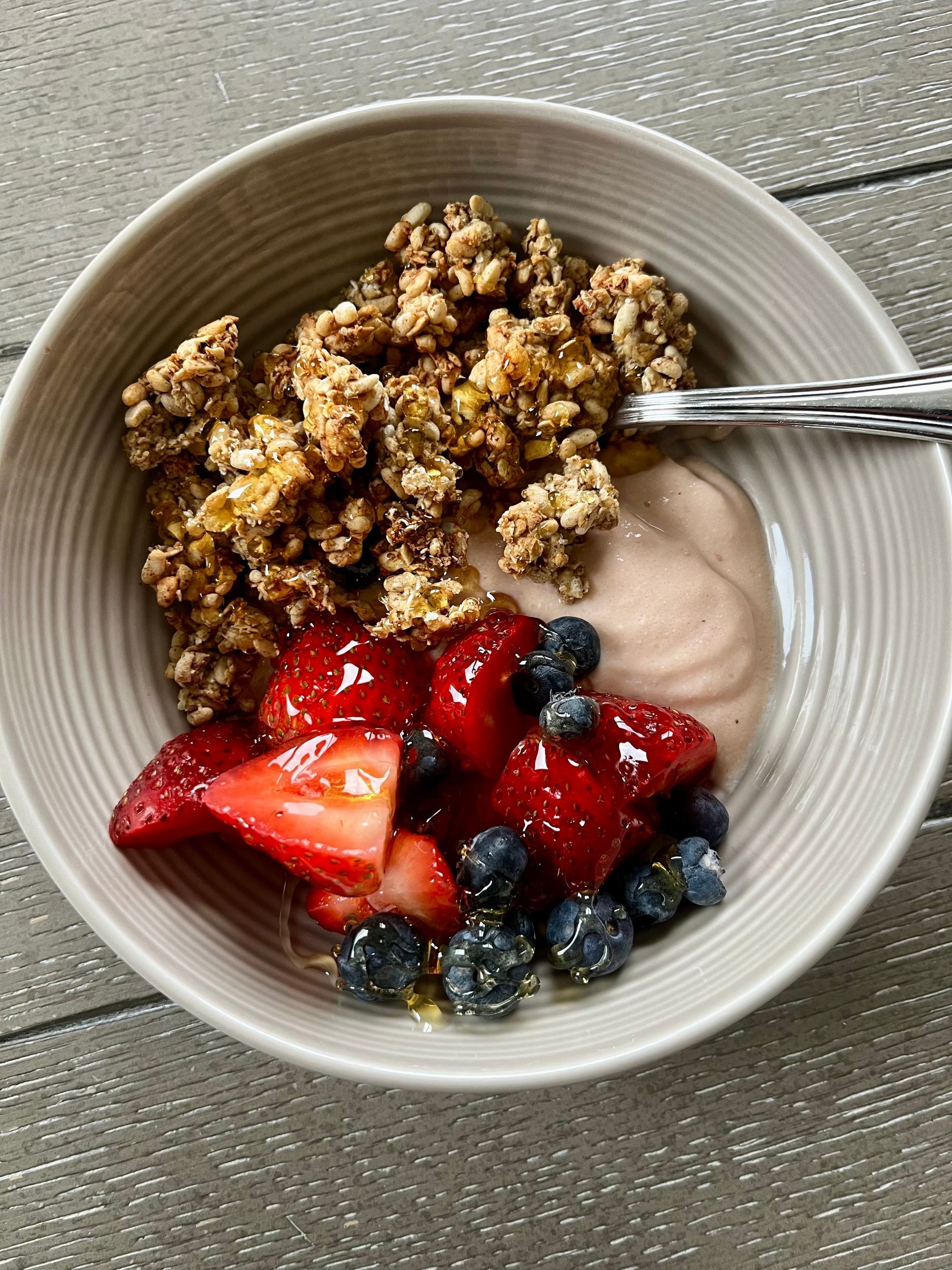 A bowl of granola and berries with a spoon in it