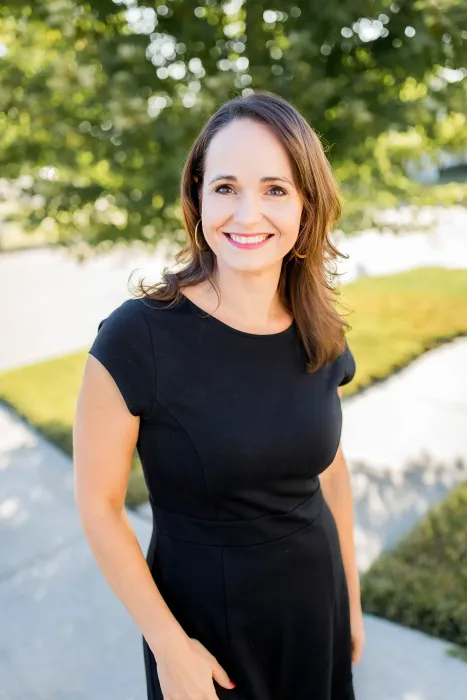 A woman is standing on one leg in front of a waterfall.