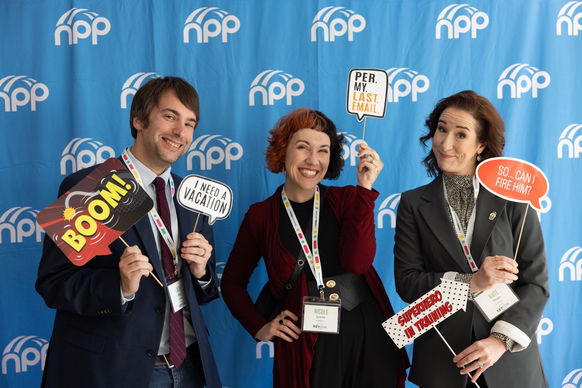 Three people smiling in front of a blue background with 