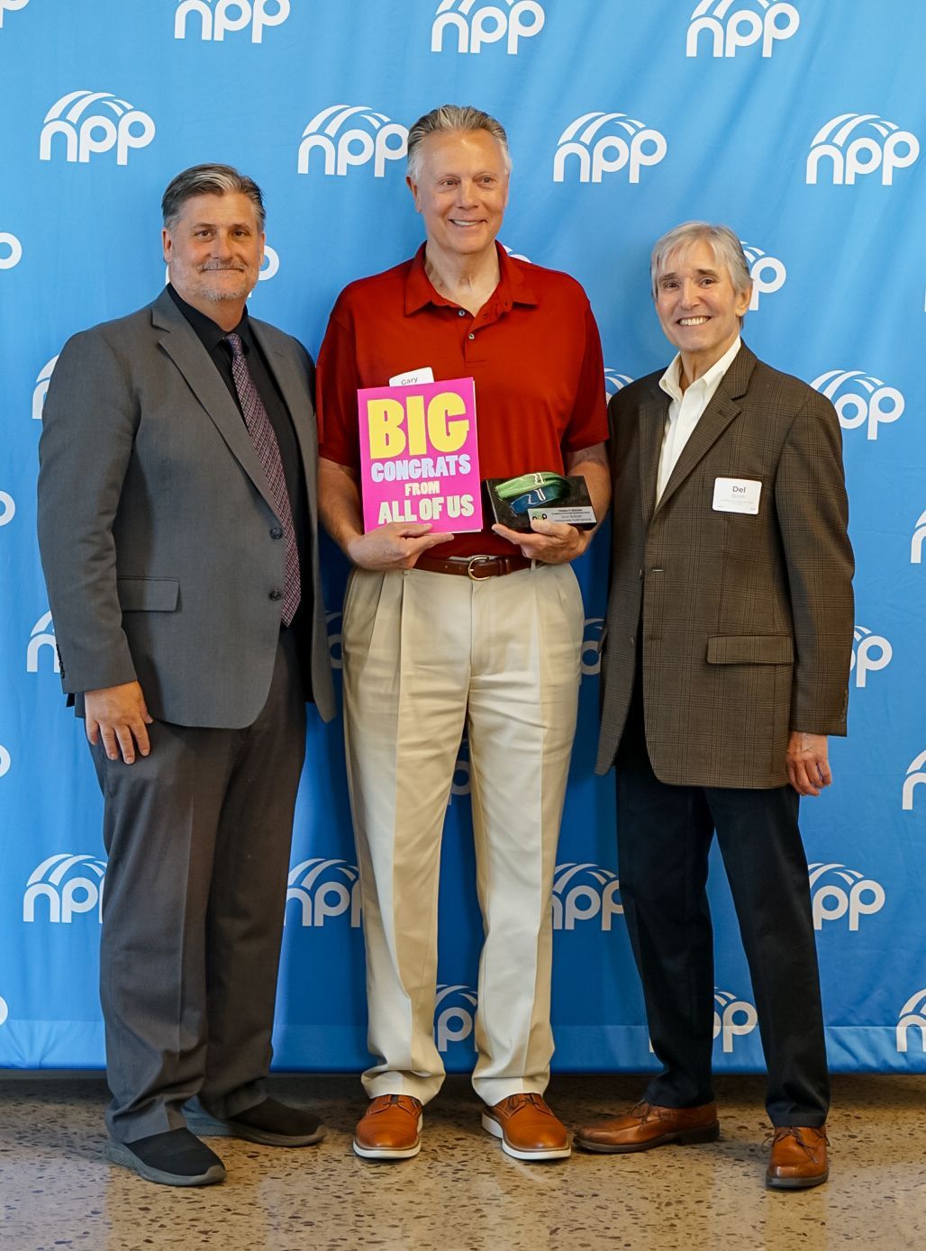 Three people stand before a blue background repeating the 