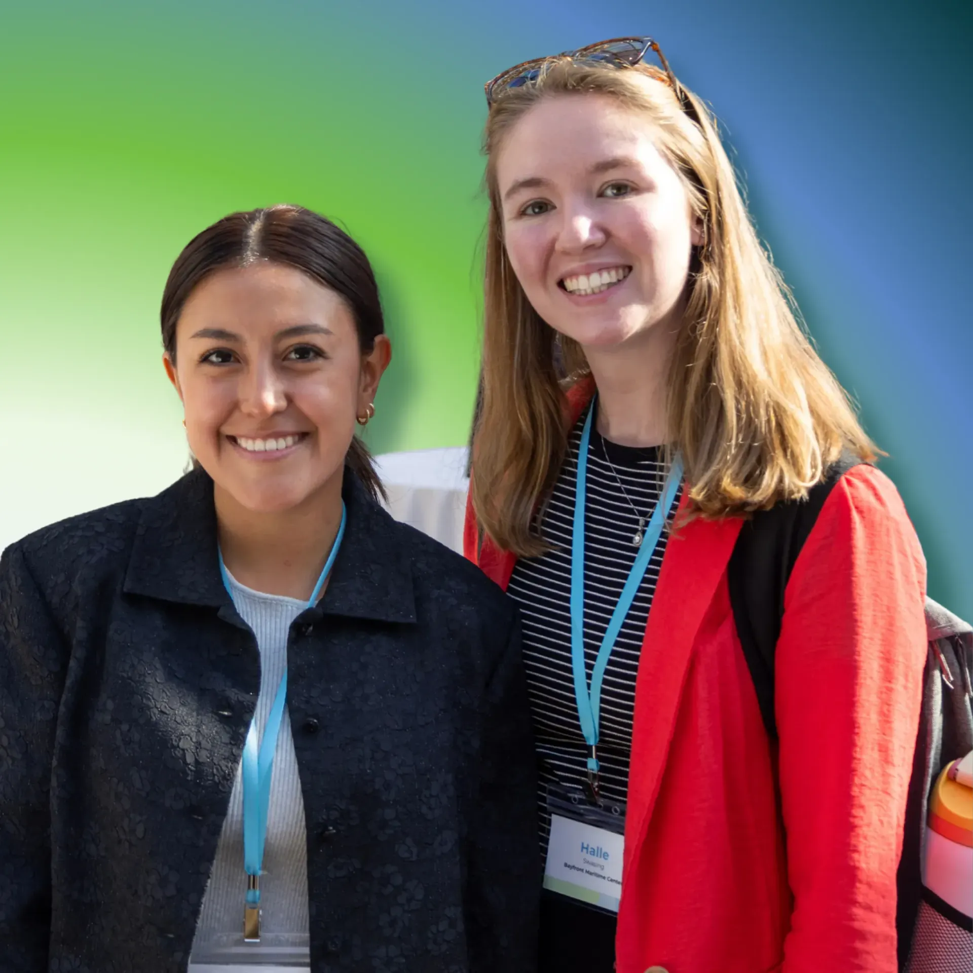 Two smiling people wearing conference name tags stand side-by-side against a green and blue background.