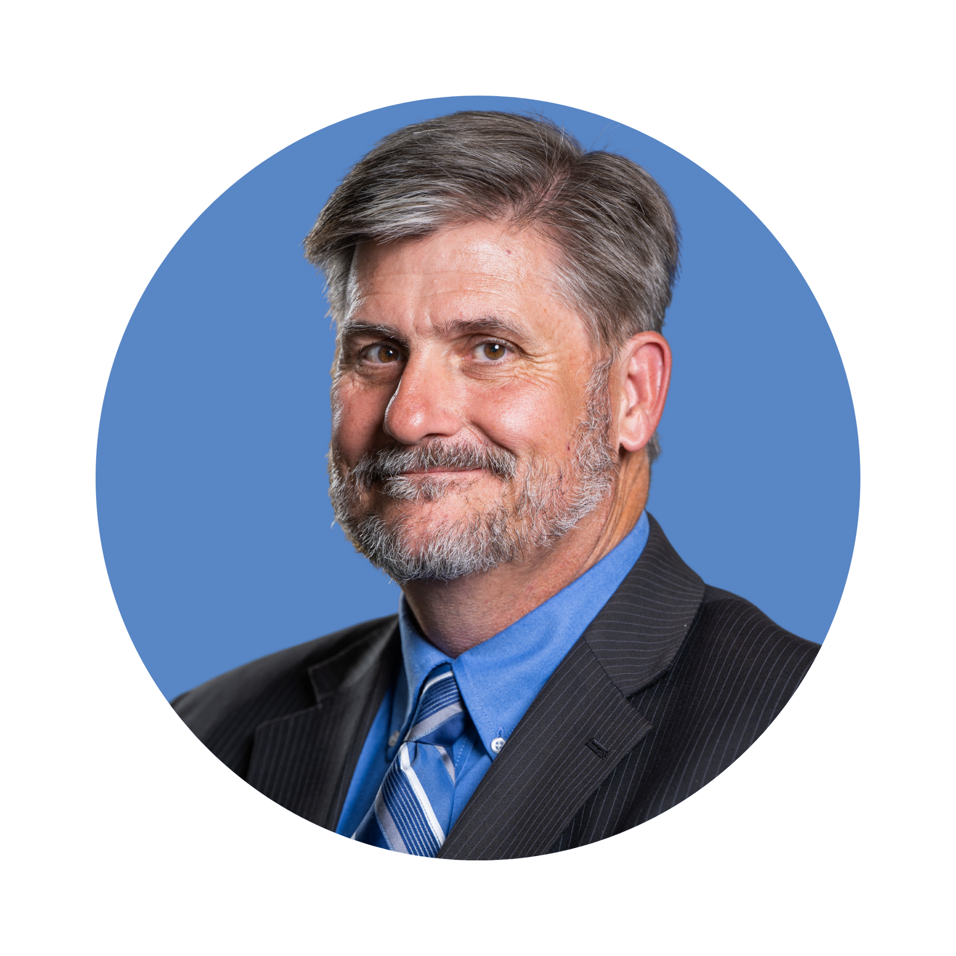 A headshot of a person with a beard, wearing a suit, blue shirt, and striped tie against a solid blue circular background.