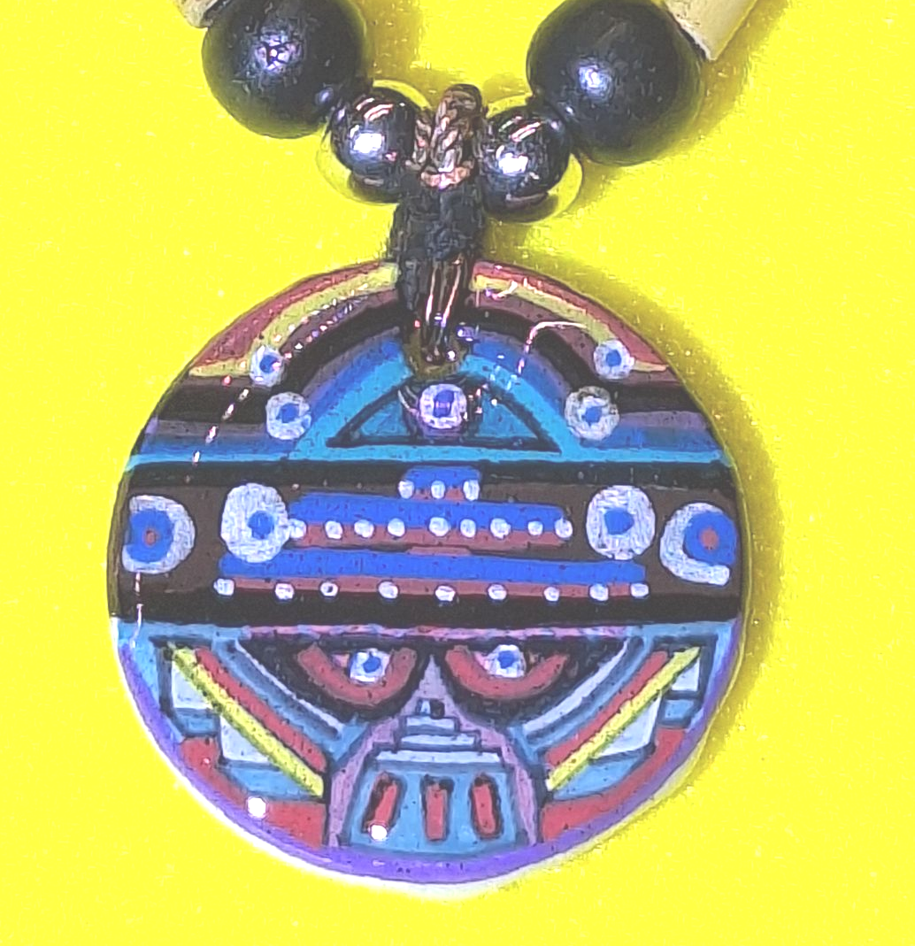 Colorful, patterned pendant with an abstract design, on a beaded necklace, against a yellow backdrop.