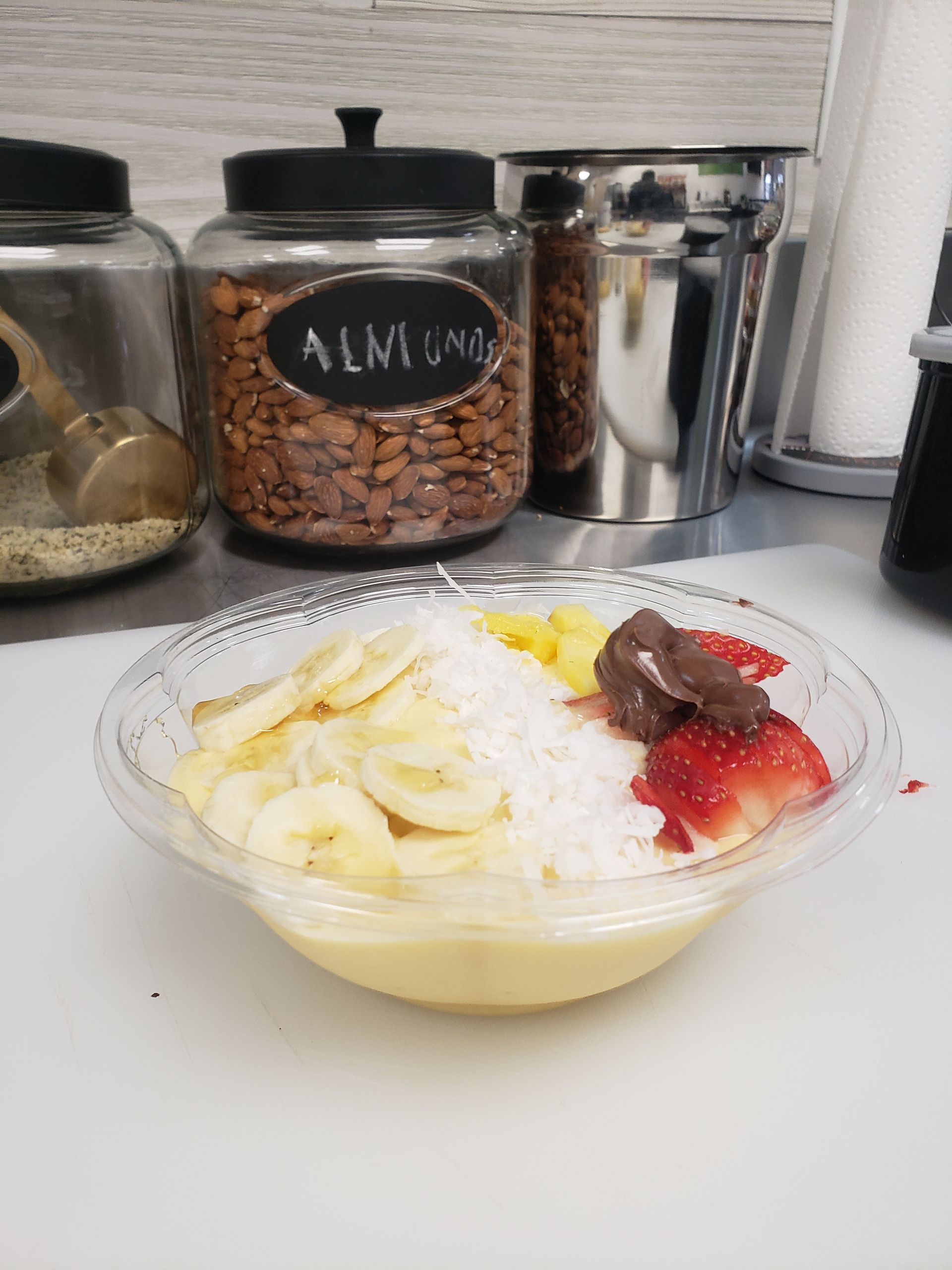 A bowl of food with bananas , strawberries and coconut on a table.