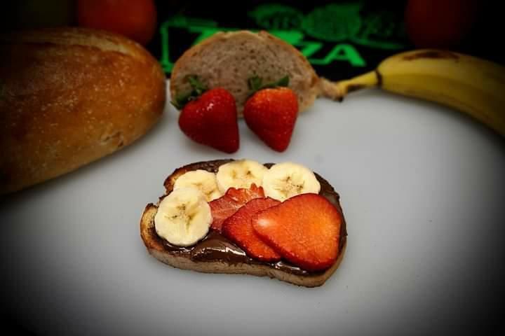 A slice of bread with bananas and strawberries on it