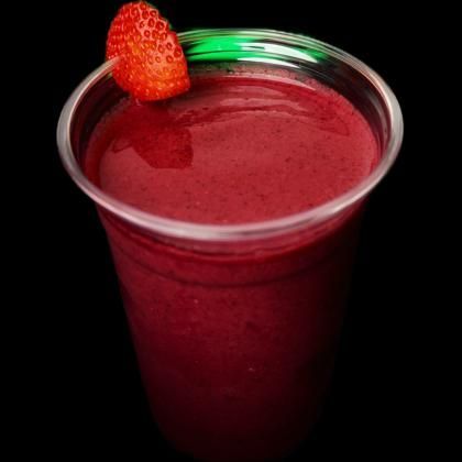 A cup of red liquid with a strawberry on top.