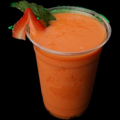 A smoothie in a plastic cup with strawberries on top