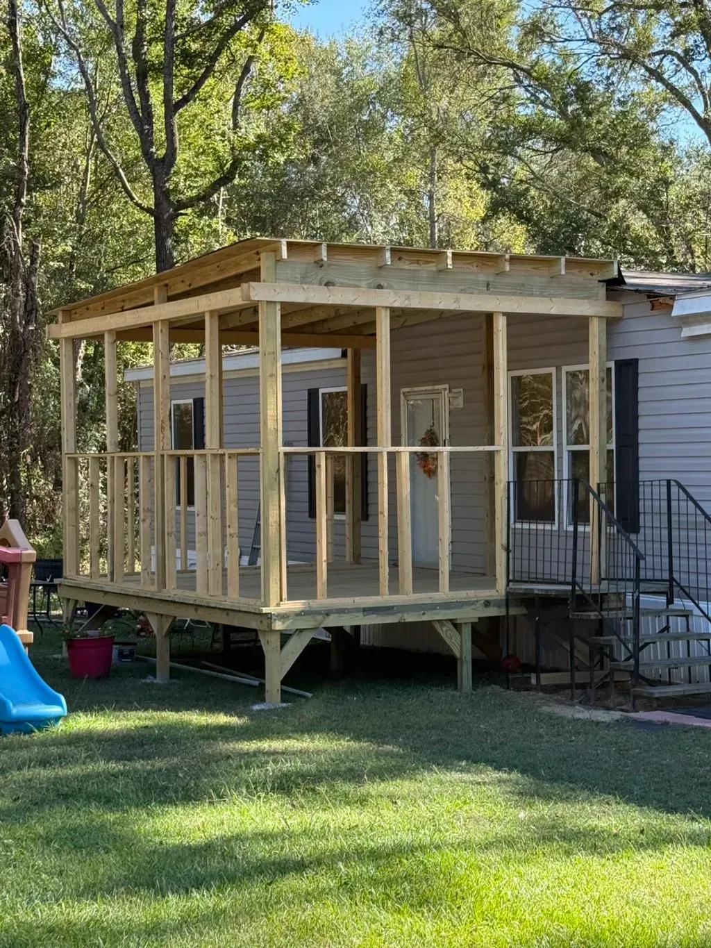 Wooden porch addition to a mobile home, under construction with lumber framework.