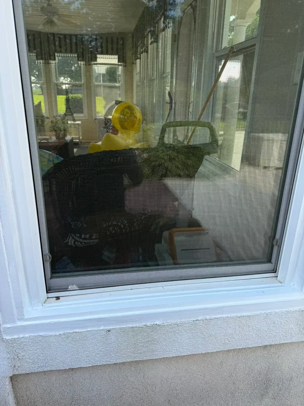 A window with a white frame reflects a room with various objects, including a yellow duck.