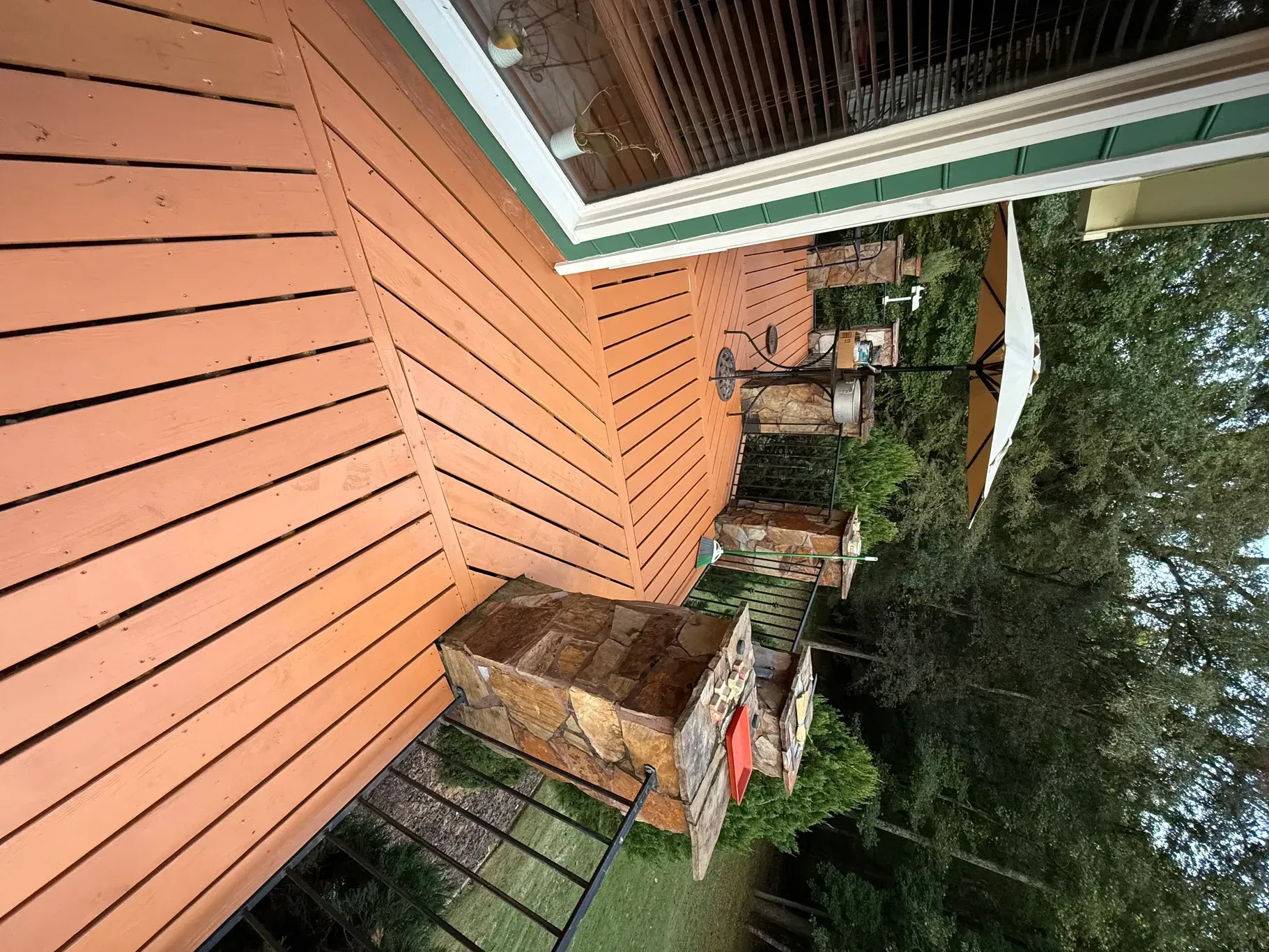 Wooden deck with a diagonal pattern, with outdoor furniture and a large umbrella.
