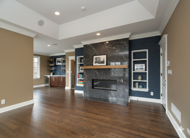 Living room with dark wood floors, marble fireplace, and built-in bookshelves.