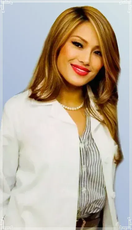 A woman wearing a white coat and a striped shirt is smiling.