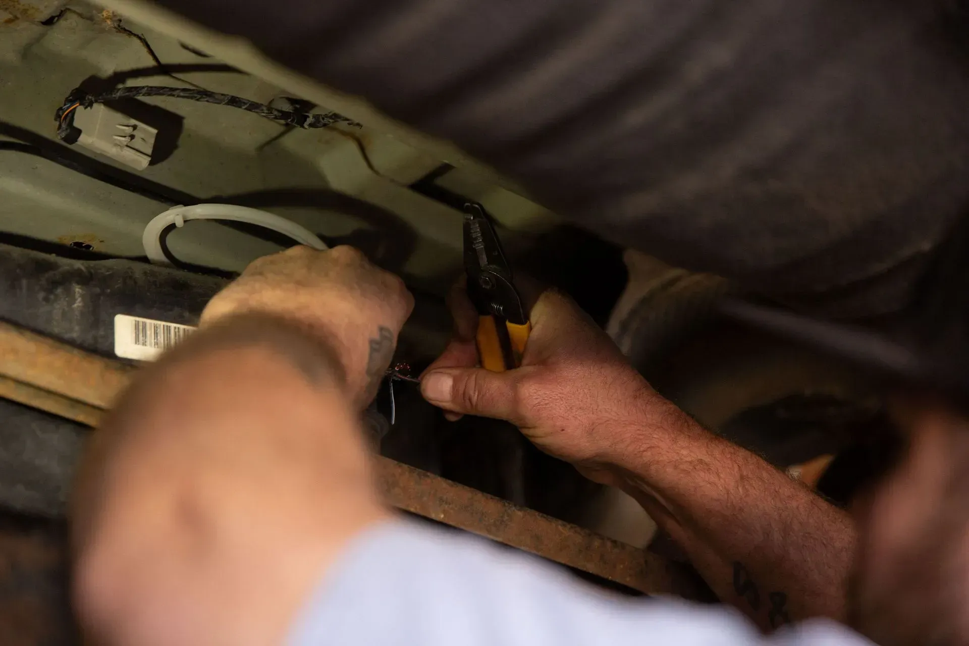Up close to technician working underneath vehicle with tools | Pat's Auto Repair & Towing