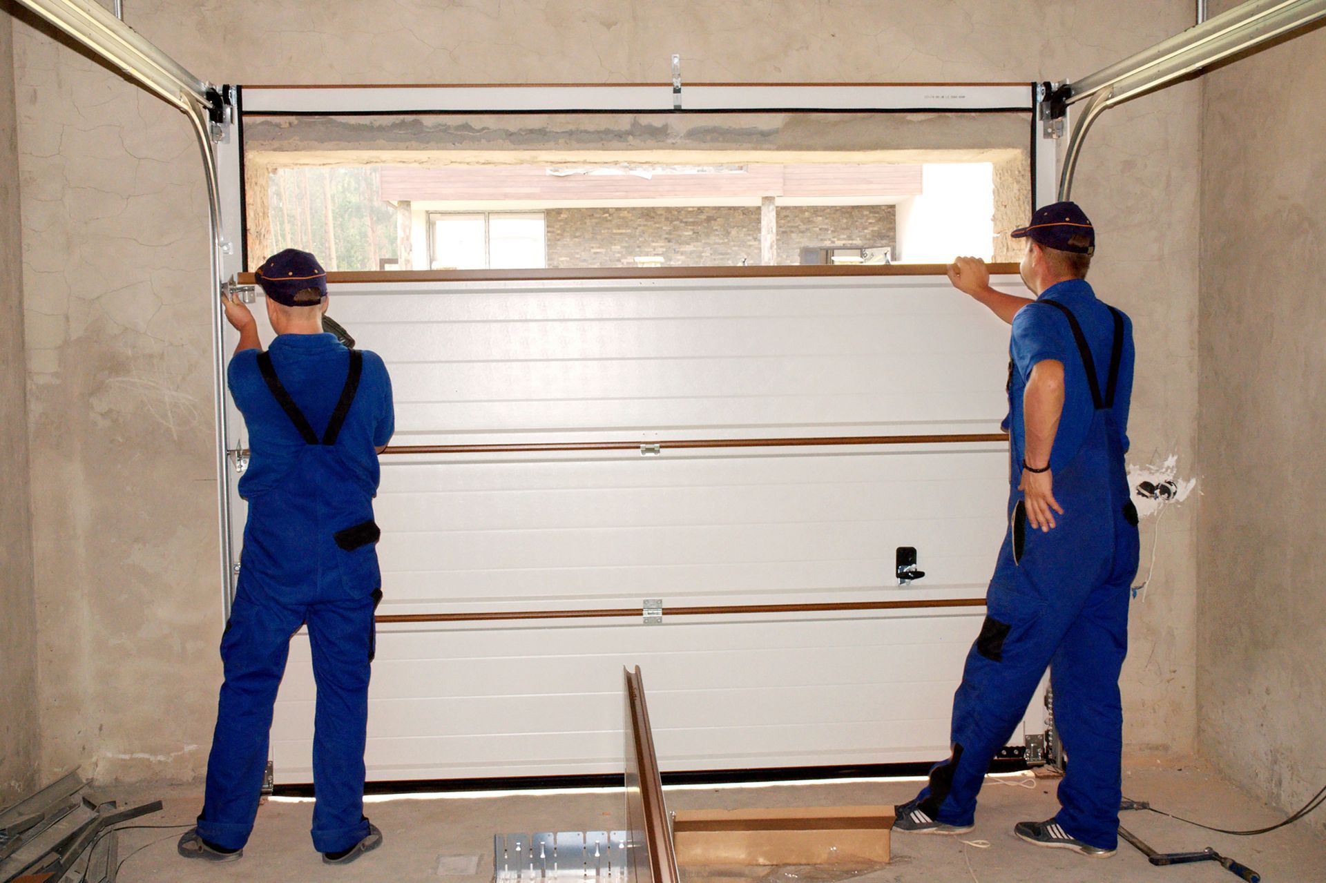 Two men are installing a garage door in a garage.
