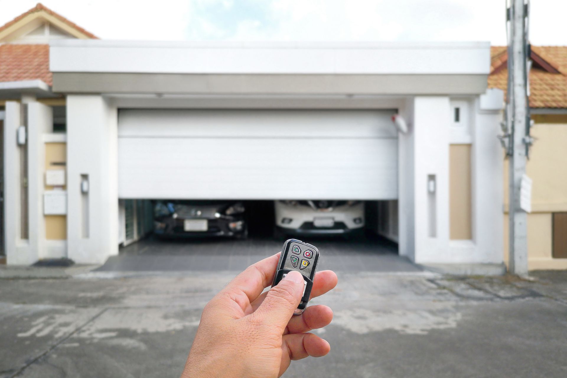 A person is holding a remote control in front of a garage door.