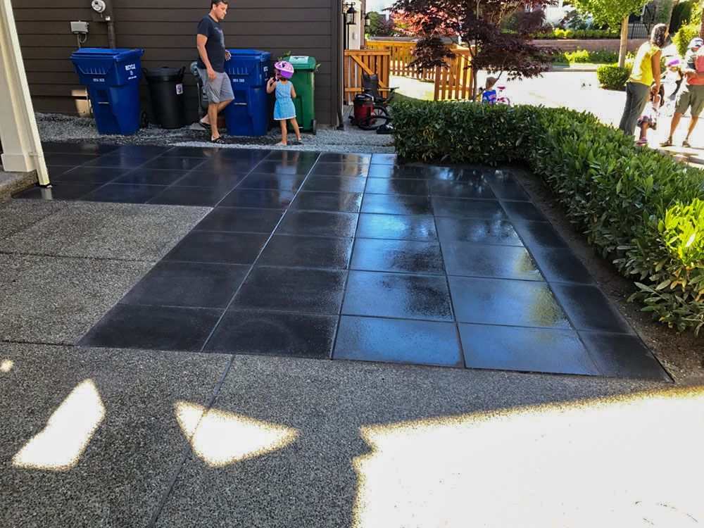 Patio with dark square tiles and gravel border; people nearby, trash cans visible.