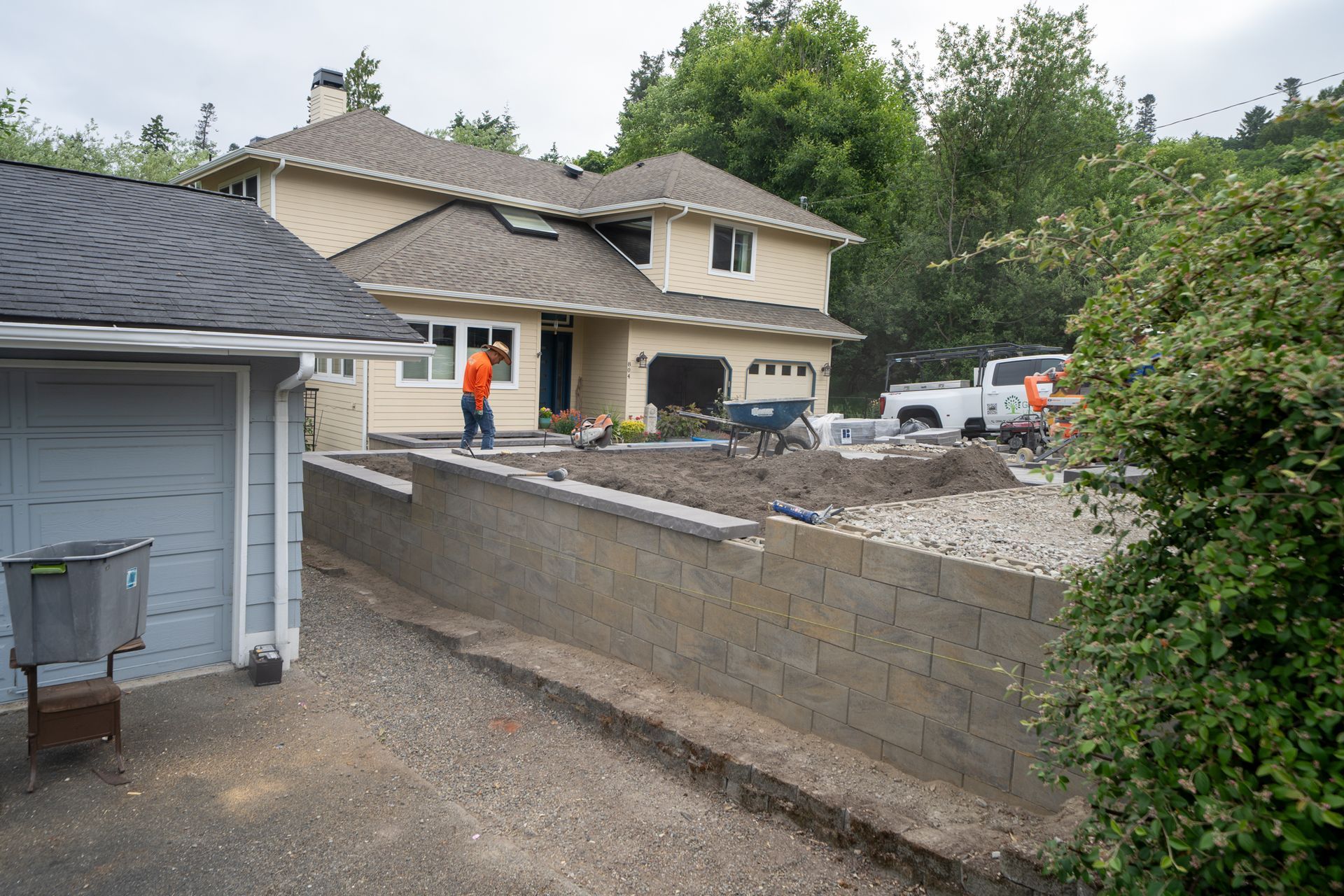 House under construction with retaining wall and gravel driveway.