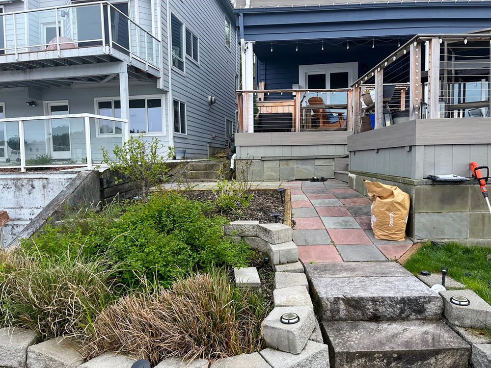 Steps and a pathway lead up to a house with a blue porch and a white house next door.