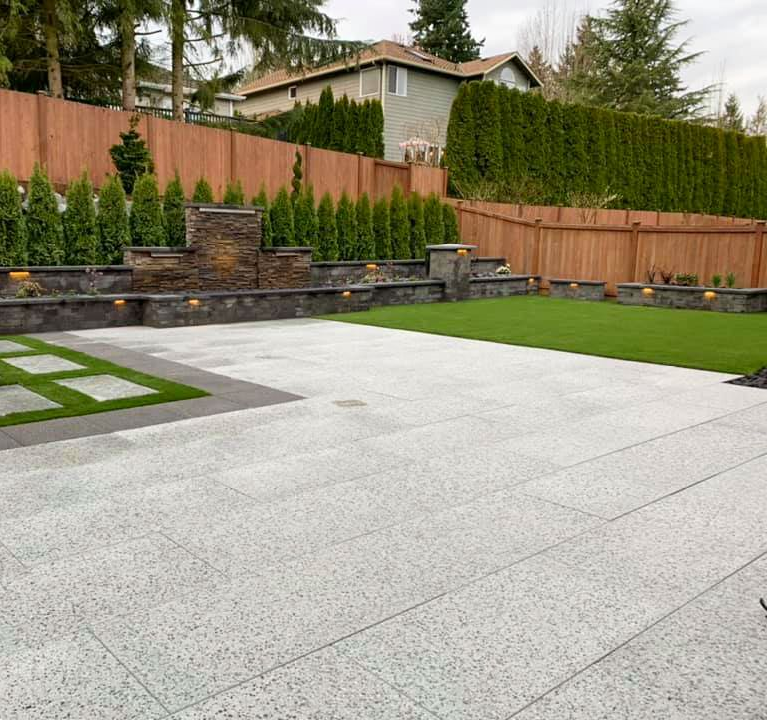 Driveway leading to a house with a row of tall green trees and a red car on the right.