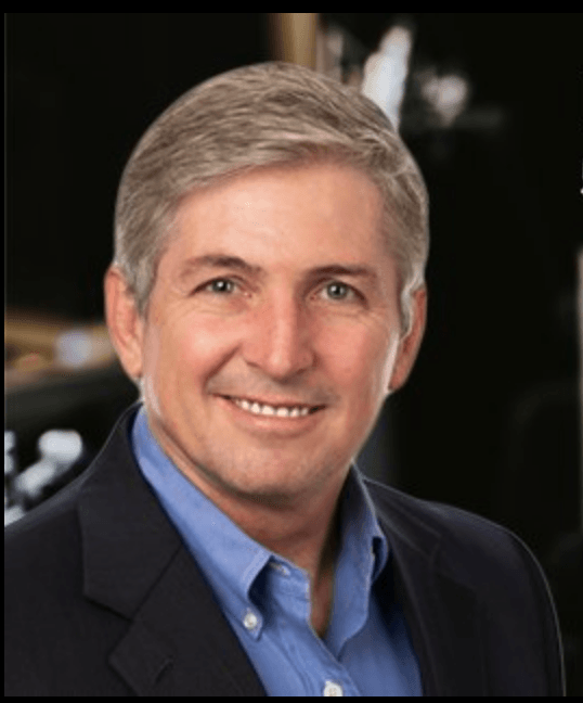 A man in a suit and blue shirt smiles for the camera