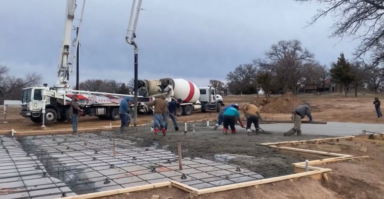 A man is pouring concrete into a wooden frame.
