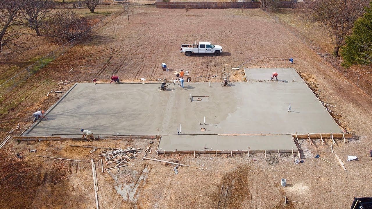 A man is pouring concrete into a wooden frame.